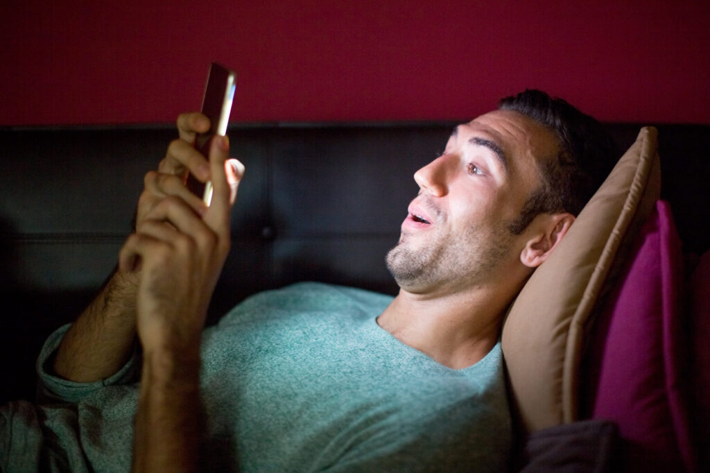 uomo steso sul divano con lo smartphone