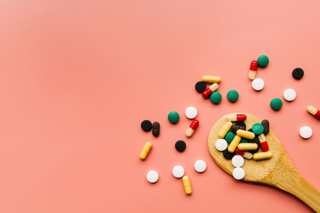 pillole di integratori colorate su un cucchiaio in legni