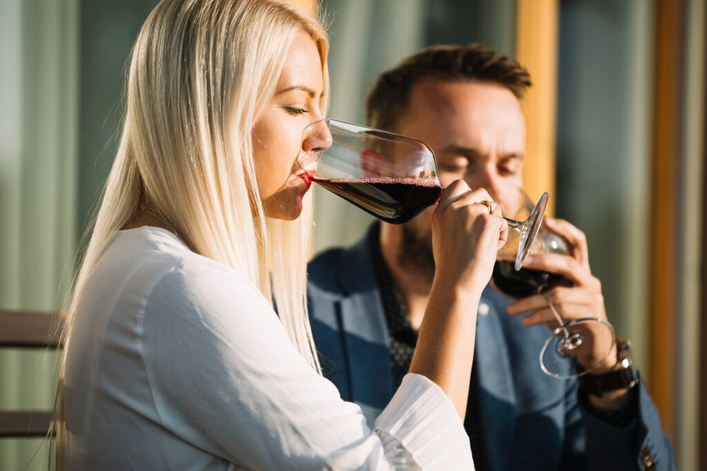 donna bionda e compagno bevono vino rosso